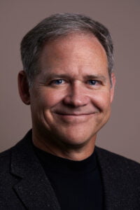 Brian Dunning, a distinguished man with gray hair, wearing a black shirt.