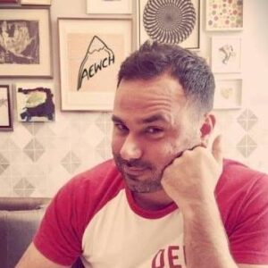 A pensive Conner Habib sits at a table, deep in thought, with his hand resting on his chin.