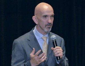Dr. Philip Goff, bald man in suit, speaking into mic.
