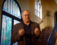 Joseph Atwill standing in front of a staircase, with a majestic window in the background.