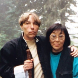 Two women, Jan Van Ysslestyne (left), and another woman, standing side by side in the woods.